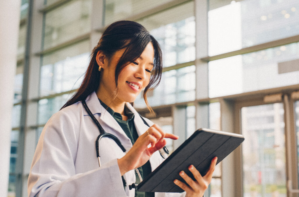 Asian woman, doctor and happy in hospital with tablet for public service, results and committed. Female person, closeup and smile for healthcare with appointment, work and wellness in medical career